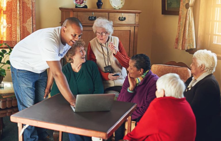 Caregiver showing seniors something on a laptop during a home sharing program in Vancouver