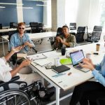 Diverse group of employees, including a man using a wheelchair, collaborating in a modern Vancouver office, representing inclusive employment and job coaching.